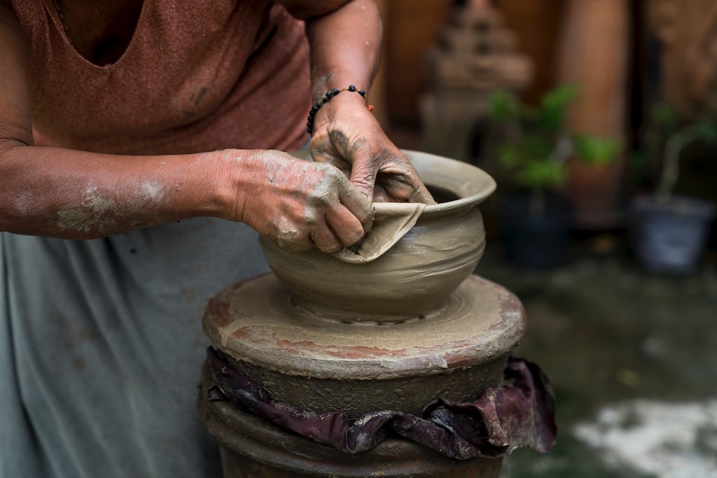 Woman making pot of clay
